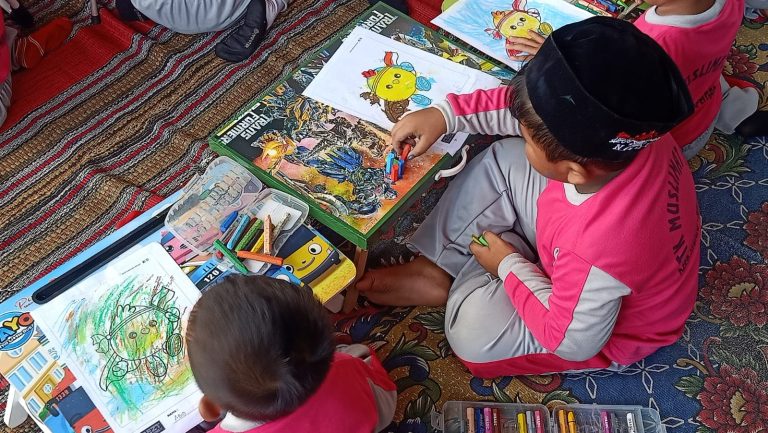 Two children sitting at the floor while coloring Coco on paper