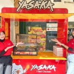 Two employees standing in front of Yasaka's booth