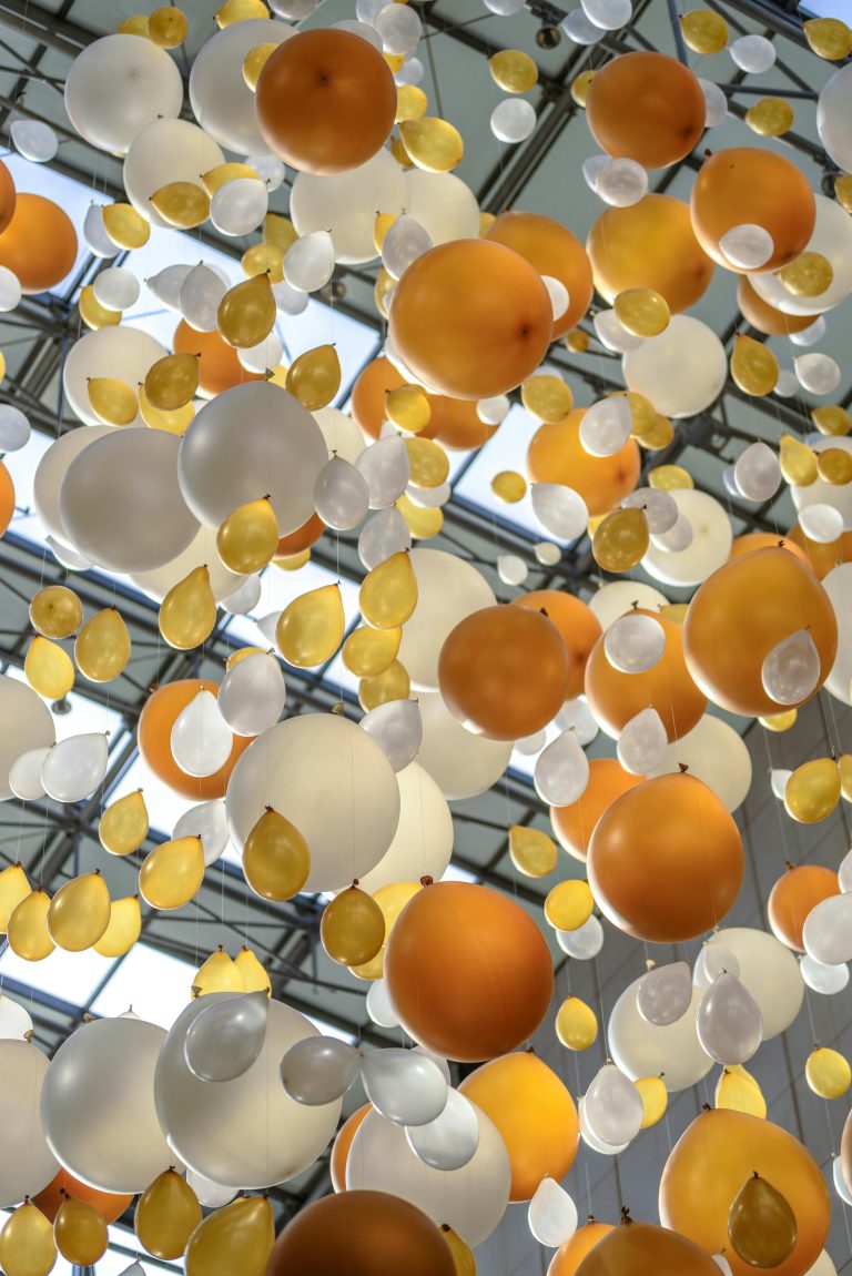 A group of yellow, white, and grey balloons floating in the sky